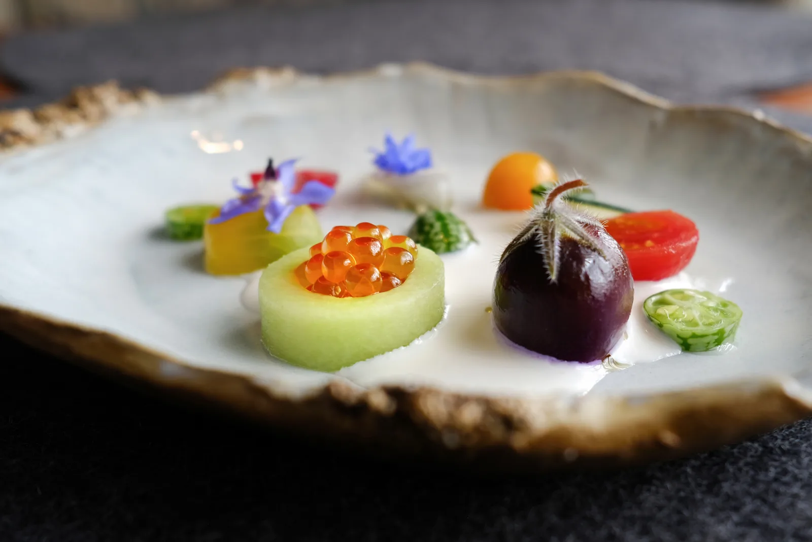 Chilled appetizer with roe and edible flowers on a shell-shaped plate at Aubergine, Carmel, food photography by Manny Espinoza