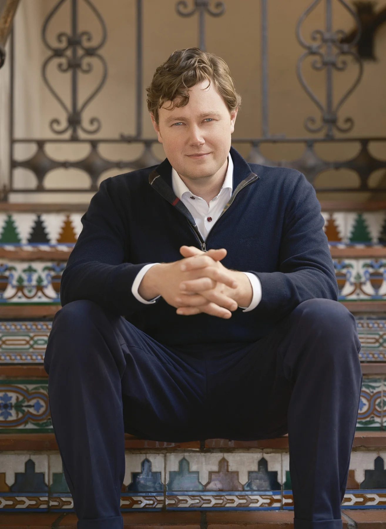 Brian Evergreen seated on a tiled Spanish stair in Carmel-by-the-Sea, hands clasped, photographed by Manny Espinoza; portraits from the session appear in Fast Company
