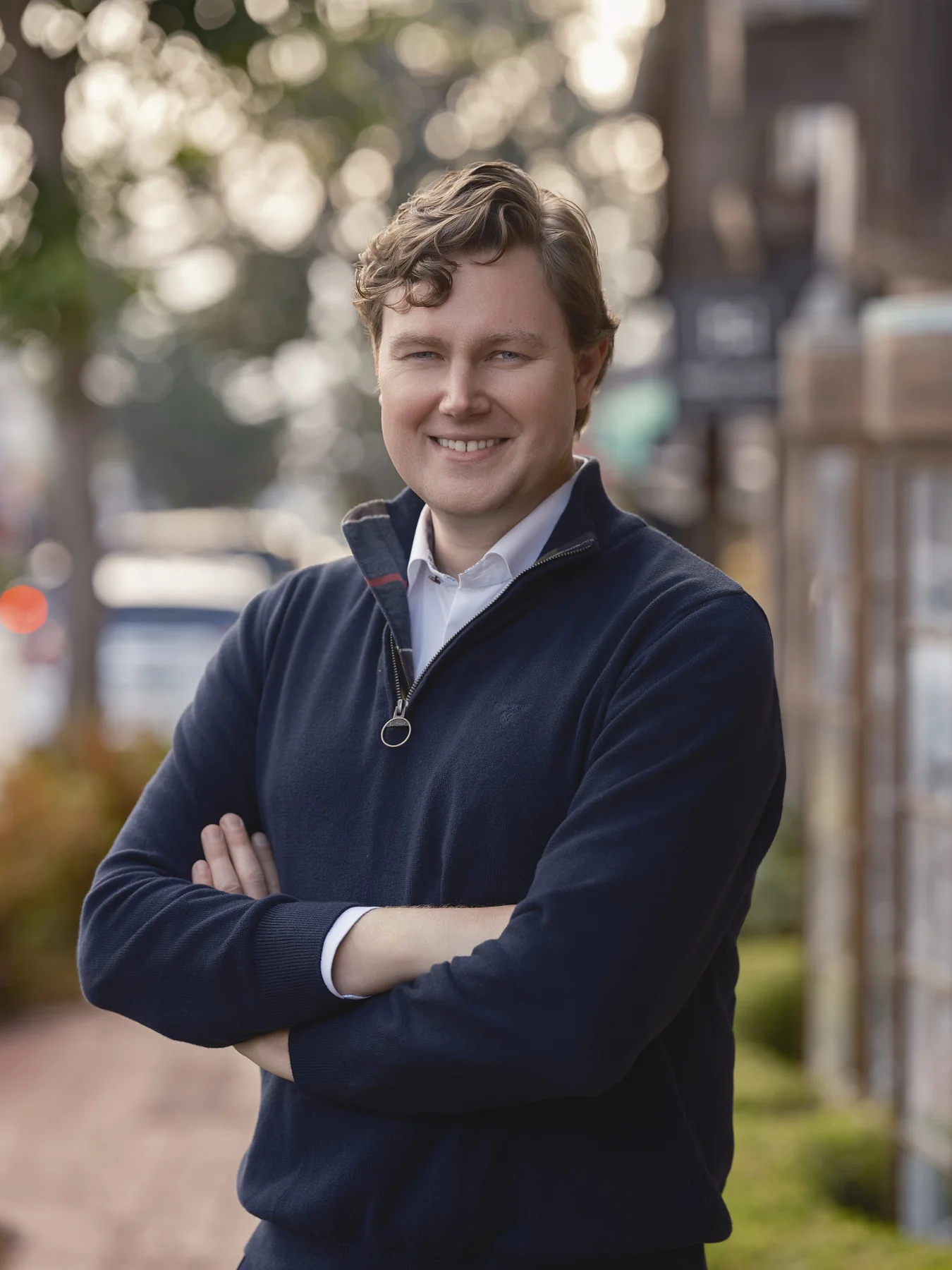 Brian Evergreen with arms crossed on a tree-lined street in Carmel-by-the-Sea in warm late-afternoon light