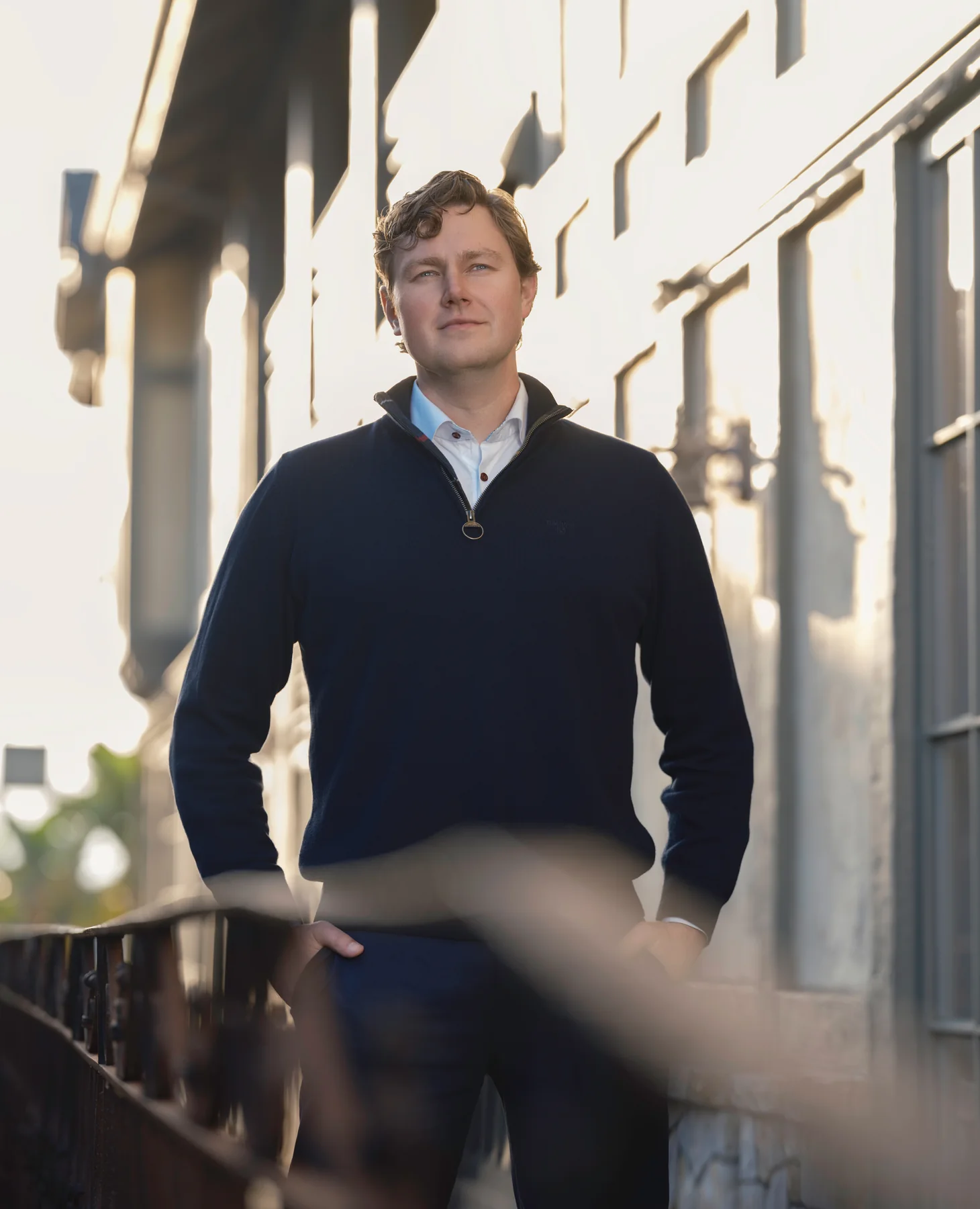 Brian Evergreen standing against a sunlit white wall in Carmel-by-the-Sea, backlit by low sun