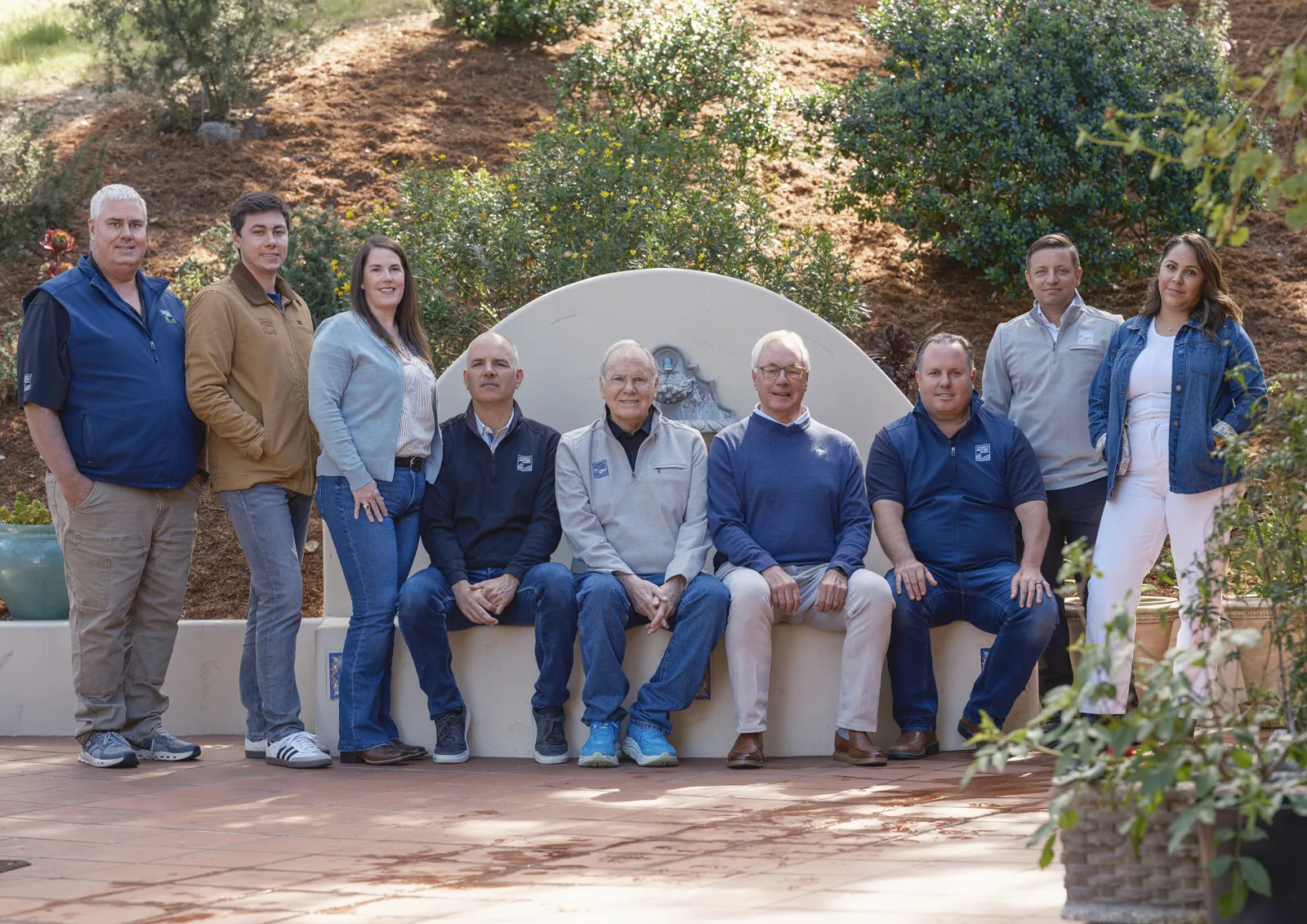Church Brothers Farms executives seated on a garden wall at the ranch, group portrait by Manny Espinoza