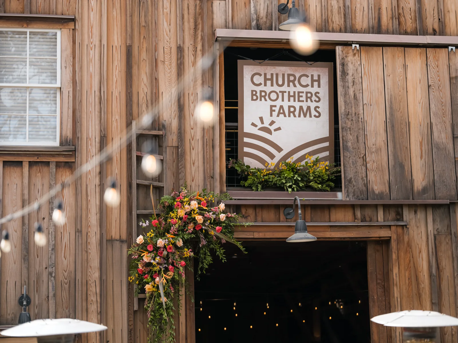 Church Brothers Farms sign framed by flowers at the entrance to The Barns at Cooper Molera, event detail by Manny Espinoza