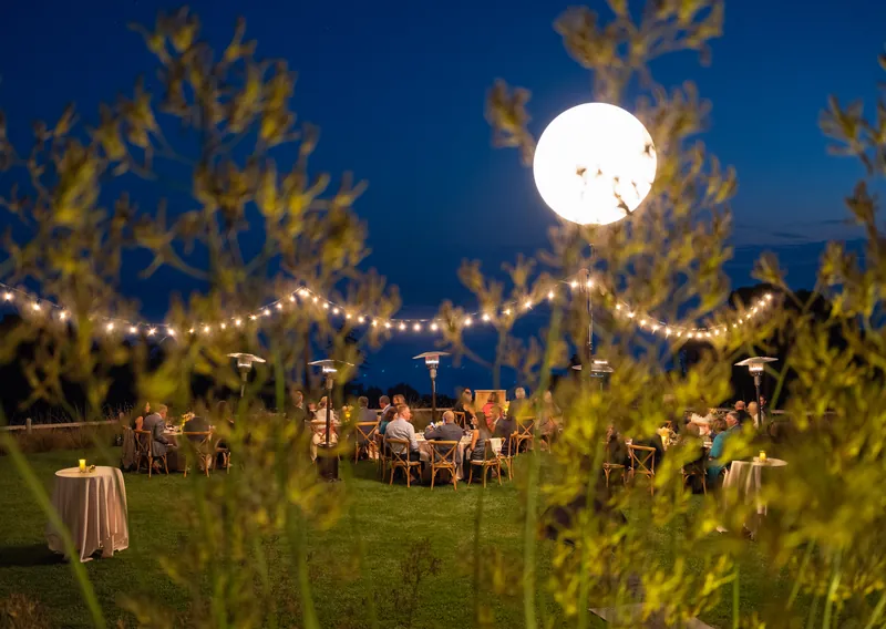Moonrise over string lights and tables at an evening corporate retreat in Big Sur, event photography by Manny Espinoza