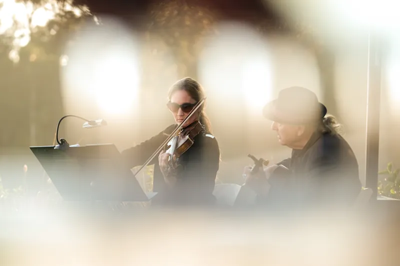 Two violinists performing at a corporate retreat in Big Sur, shot through glowing bokeh, event photography by Manny Espinoza