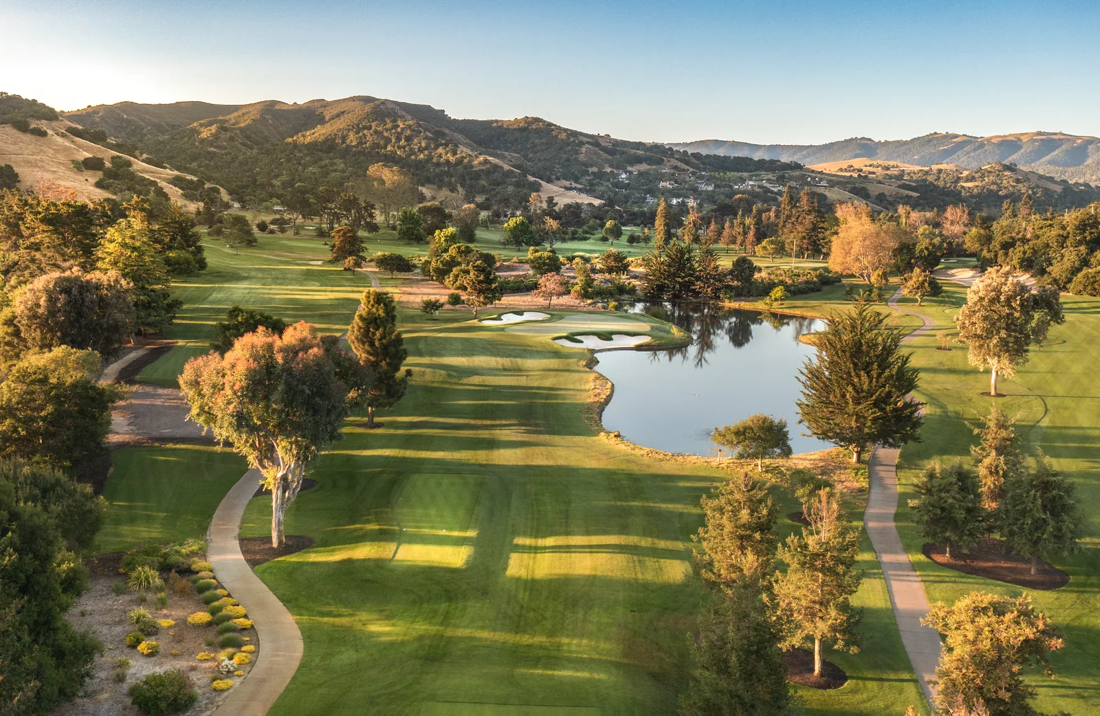 Aerial drone photograph of a golf course lake and fairways at Corral de Tierra in warm evening light