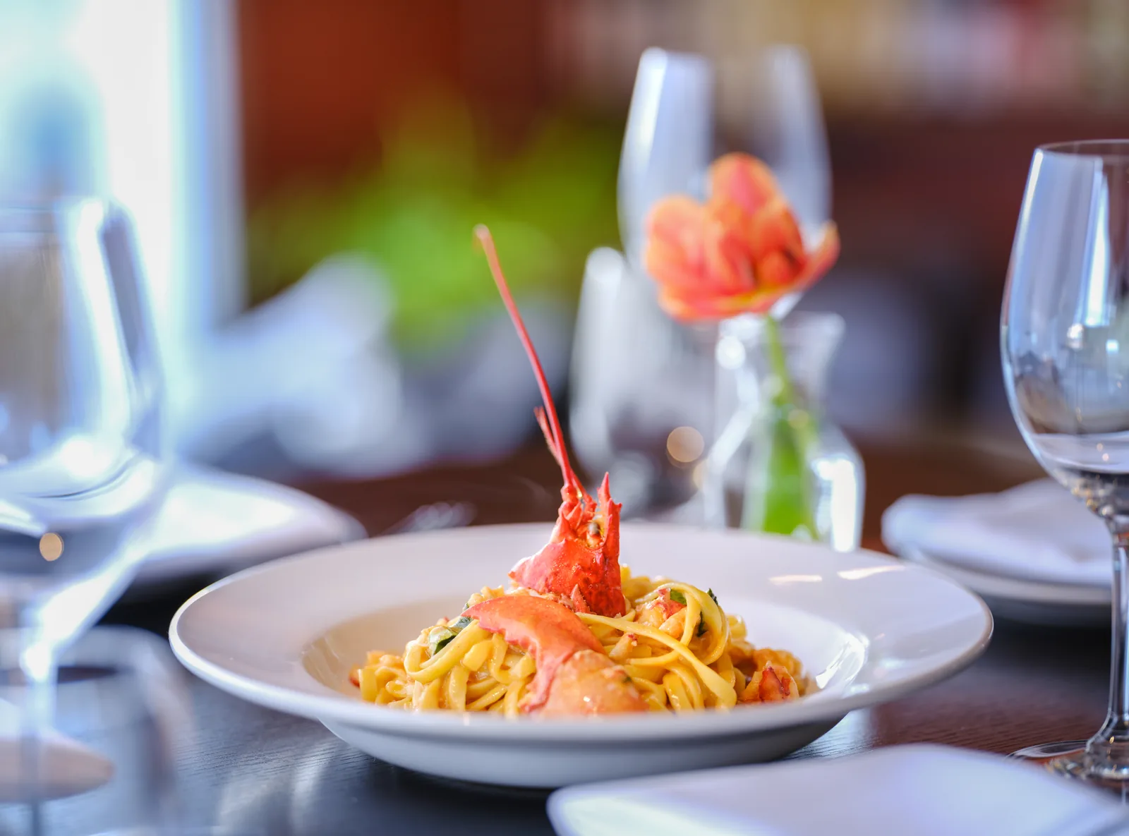 Lobster pasta with a tulip in a bud vase on the table at Mezzaluna, restaurant food photography by Manny Espinoza