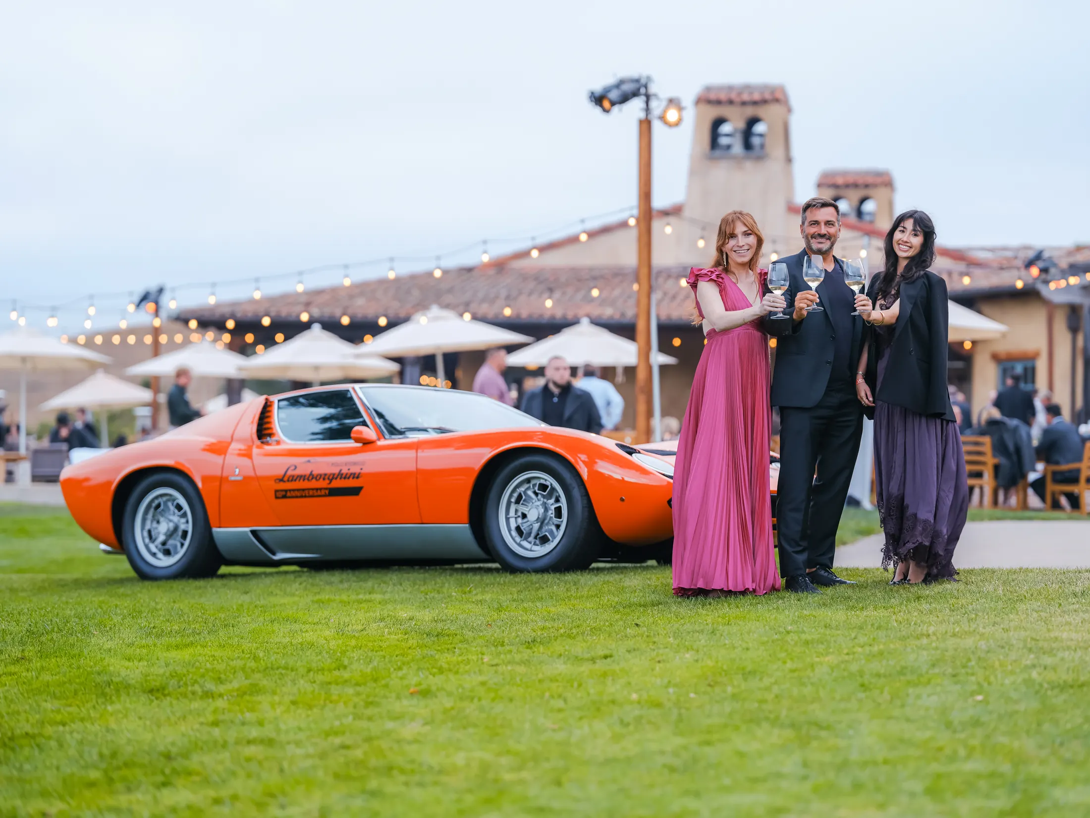 Roberto Loppi, Michelle Kofman, and Mia Roig of Moët Hennessy toasting beside a Lamborghini Miura at the Serata Italiana, TPC Pasadera
