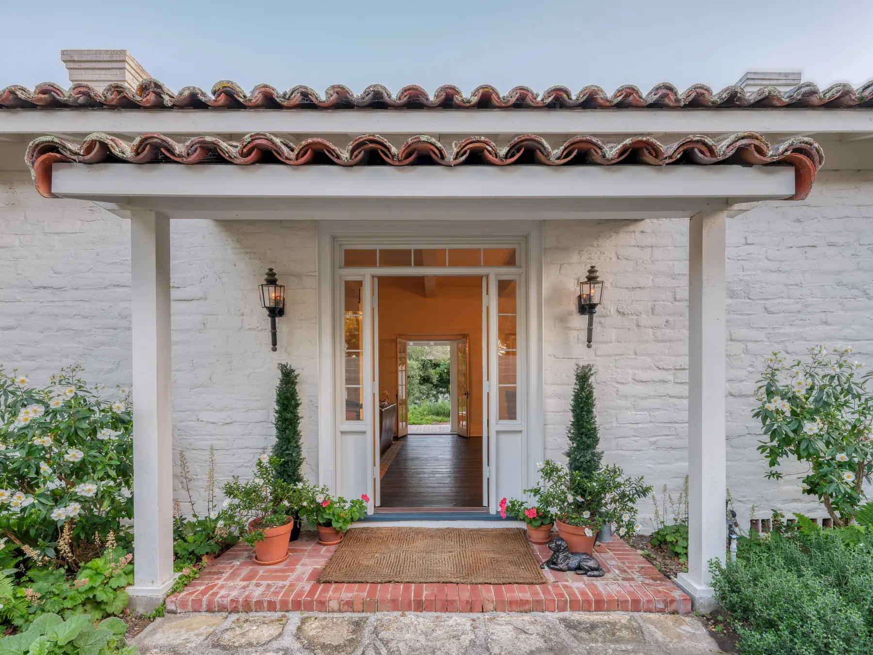 Front entry of the 1940 Robert Stanton adobe in Monterey with red tile roof, whitewashed adobe brick and potted plants