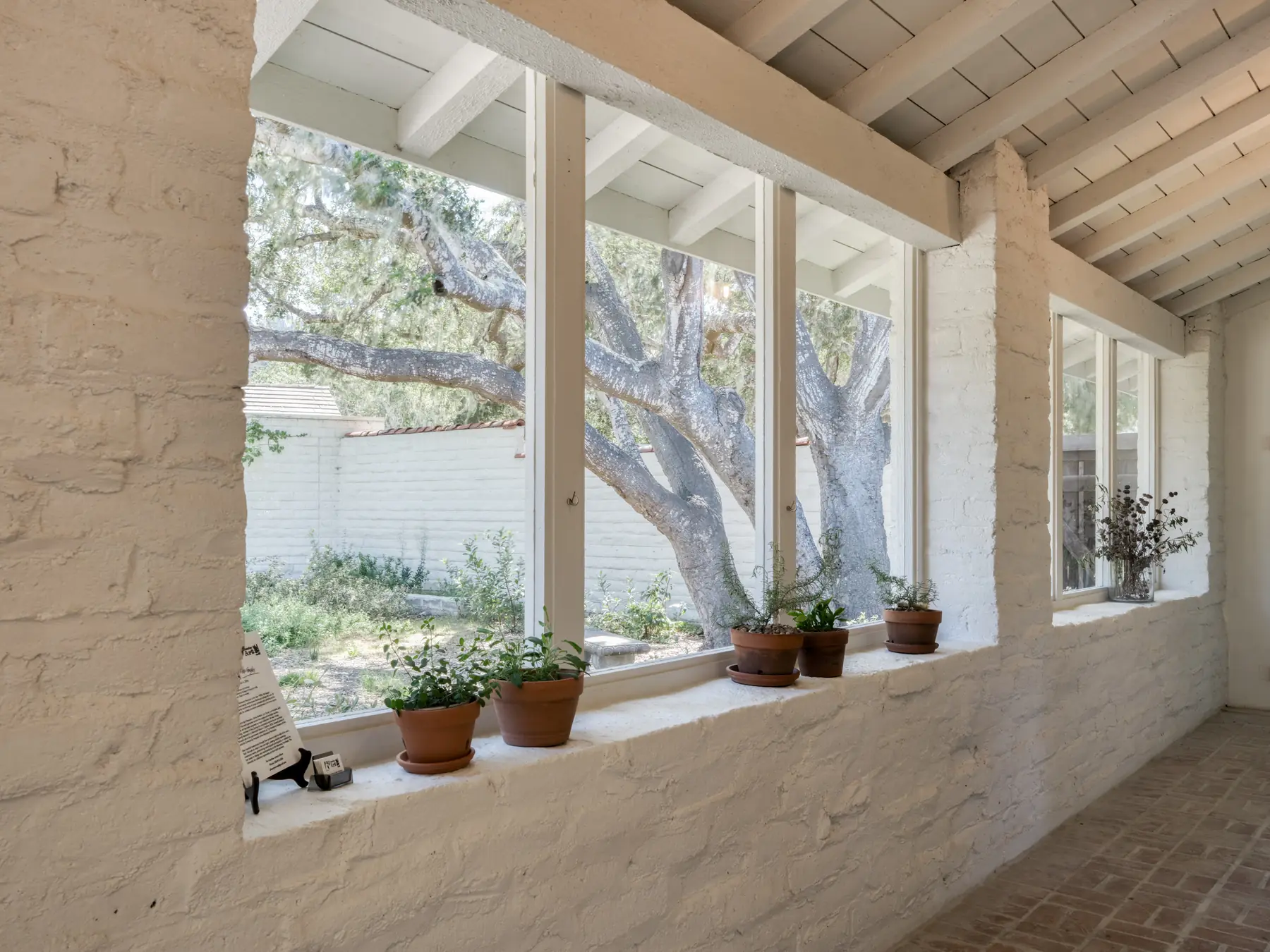 Deep window reveals in the 20-inch adobe walls of 150 Littlefield Road, Monterey, looking out to live oaks