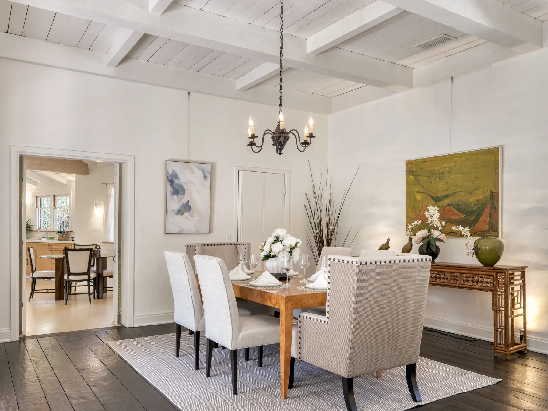 Dining room of the 1940 Monterey adobe with white beamed ceiling, iron chandelier and French doors