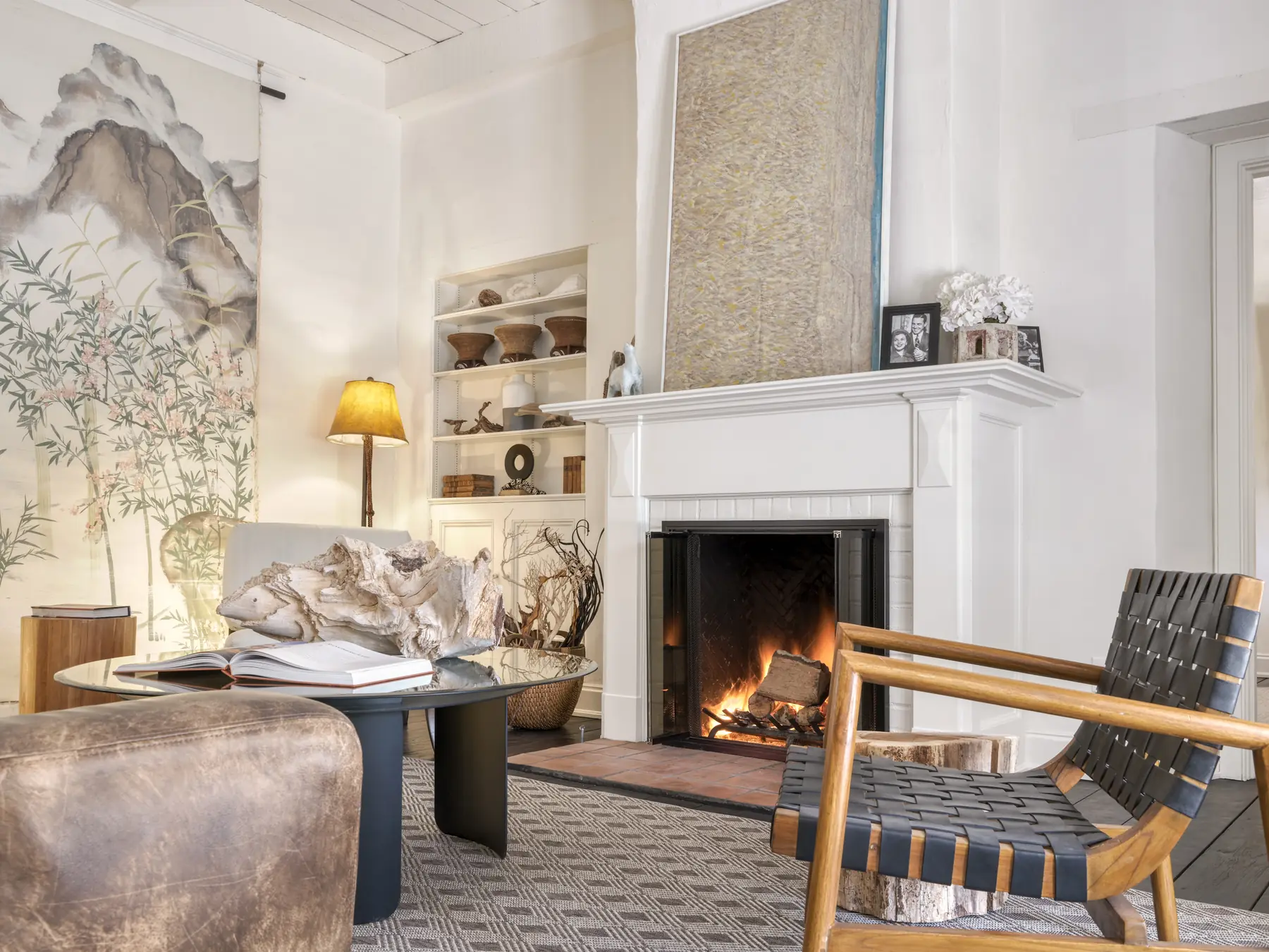 Living room of Shirley Temple's wedding house in Monterey, the original fireplace lit, whitewashed adobe walls and beamed ceiling
