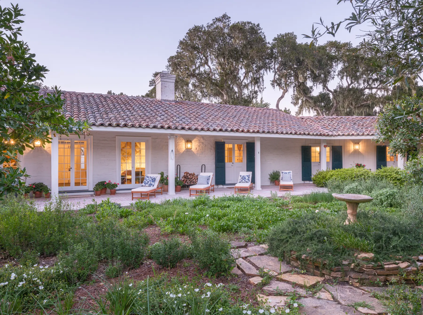 Rear elevation and walled garden of the 1940 adobe at 150 Littlefield Road, Monterey, under live oaks with the loggia and patio furniture