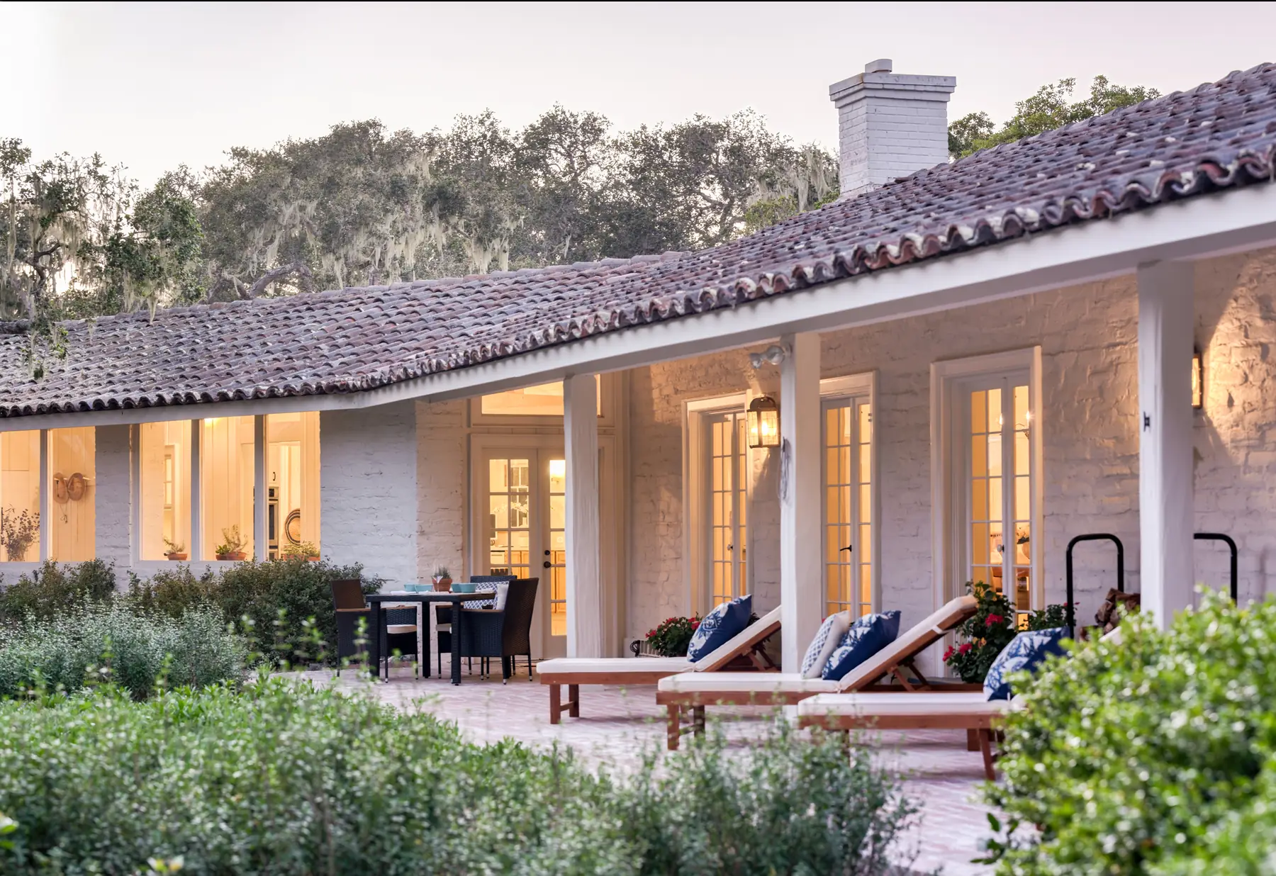 Twilight exterior of the 1940 white adobe at 150 Littlefield Road, Monterey, loggia lit under the tile roof, where Shirley Temple was married in 1950