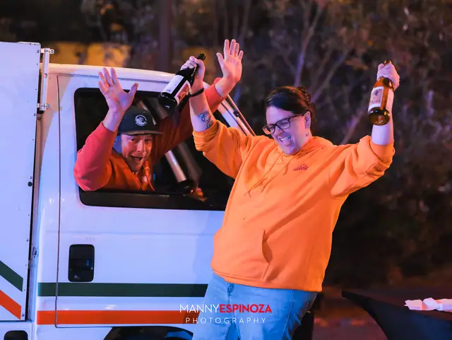 Man waving a bottle from the window of a catering truck while a colleague cheers at Taste of Carmel 2026