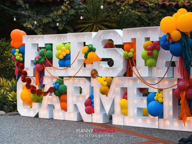 The FIESTA CARMEL marquee sign wrapped in colorful balloons at the Carmel Mission at Taste of Carmel 2026