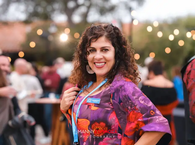 Woman in a purple floral kimono and Chamber lanyard smiling at Taste of Carmel 2026