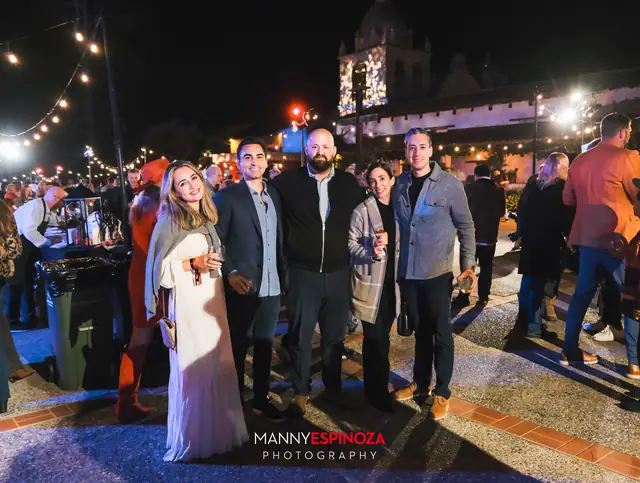 Guests posing at night with the Carmel Mission bell tower behind them at Taste of Carmel 2026