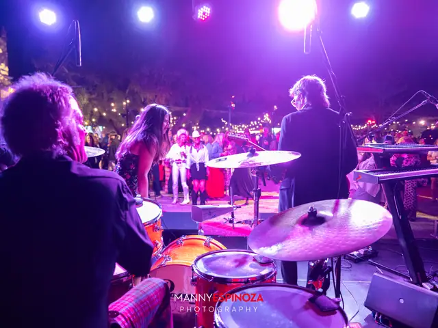The band on stage under purple and red lights, seen from behind the drum kit, at Taste of Carmel 2026