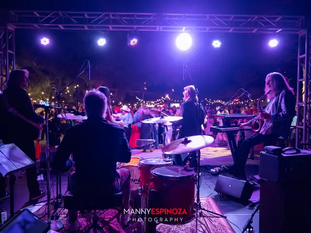 The band on stage under purple and red lights, seen from behind the drum kit, at Taste of Carmel 2026