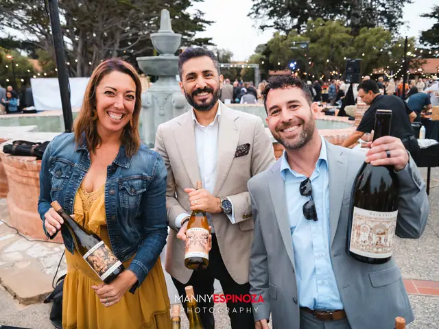 Three guests holding magnum bottles of wine in front of the Carmel Mission courtyard fountain at Taste of Carmel 2026