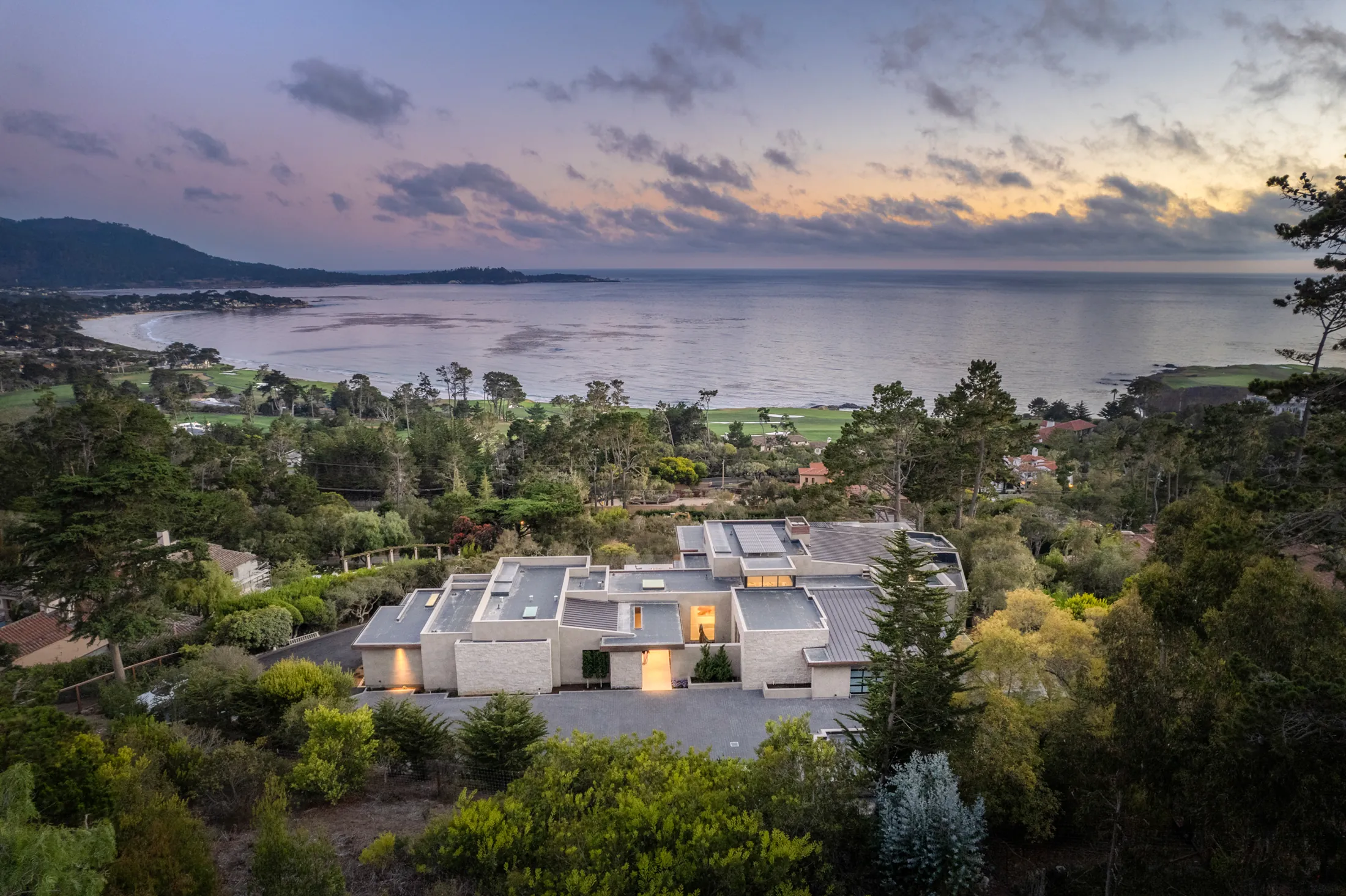 Dusk aerial of The Edge in Pebble Beach with Carmel Bay, Pebble Beach Golf Links, and Point Lobos beyond, by Manny Espinoza