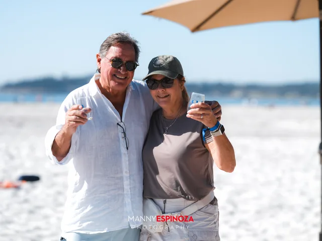 A couple toasting with the bay behind them at Walk for Freedom 2026 on Carmel Beach