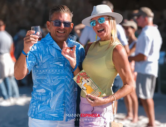 A couple, one in a blue shirt and one in a white hat, toasting at Walk for Freedom 2026 on Carmel Beach