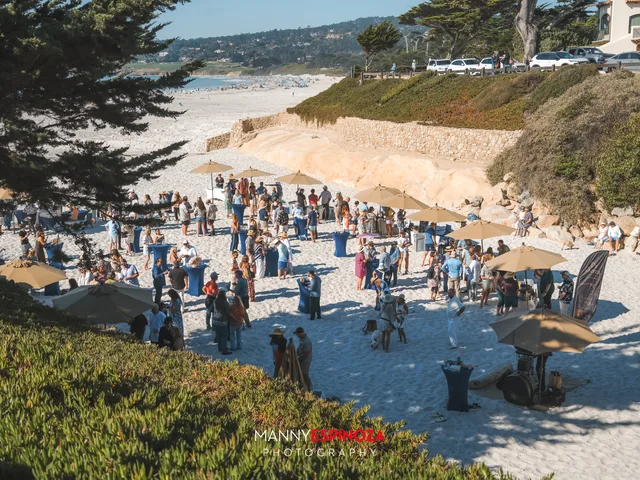 The reception seen from the Scenic Road bluff, umbrellas scattered on the sand at Walk for Freedom 2026 on Carmel Beach
