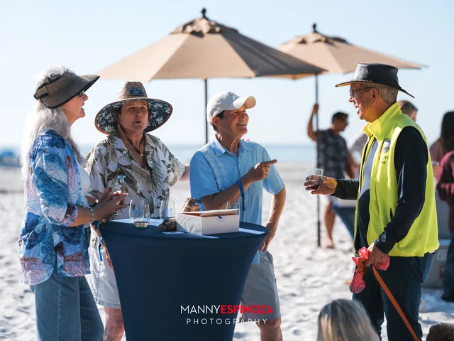 Guests in Hawaiian shirts at a cocktail table under an umbrella at Walk for Freedom 2026 on Carmel Beach