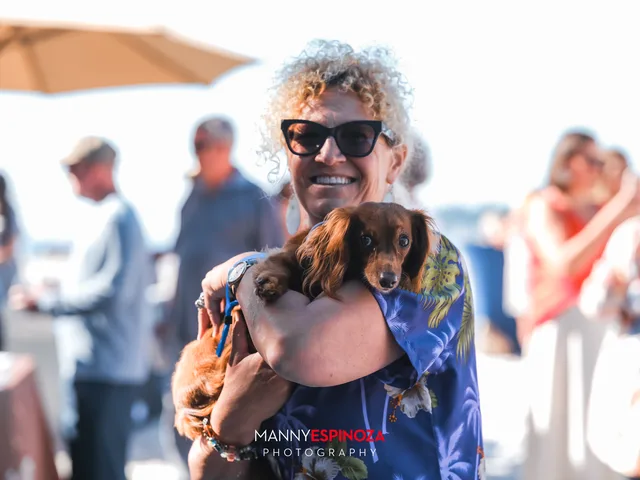 A guest with curly hair cradling a dachshund at Walk for Freedom 2026 on Carmel Beach