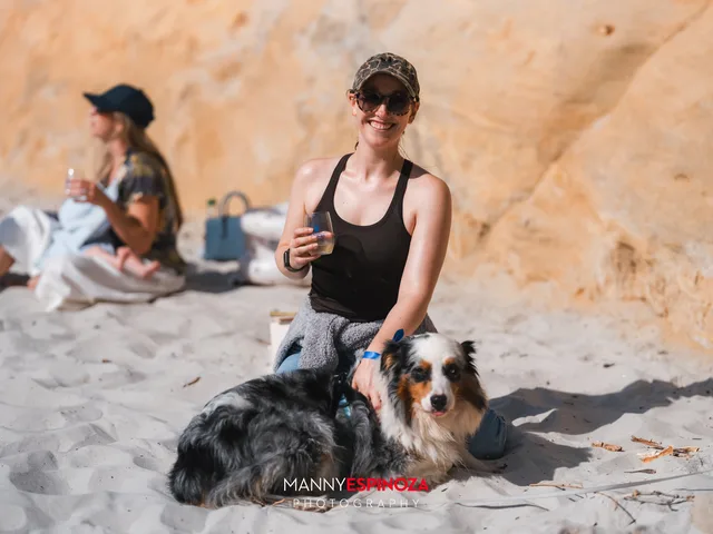 A guest kneeling in the sand with her Australian shepherd at Walk for Freedom 2026 on Carmel Beach
