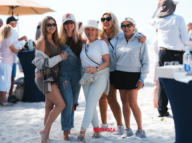 A group of friends posing with drinks under the umbrellas at Walk for Freedom 2026 on Carmel Beach