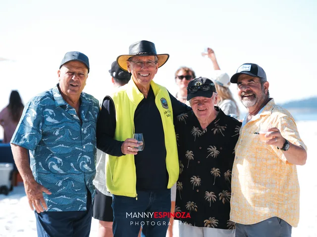 Four men toasting, one in a yellow jacket at Walk for Freedom 2026 on Carmel Beach