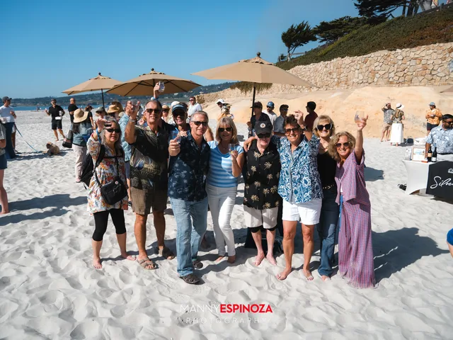 A big group of guests posing under the umbrellas with arms raised at Walk for Freedom 2026 on Carmel Beach
