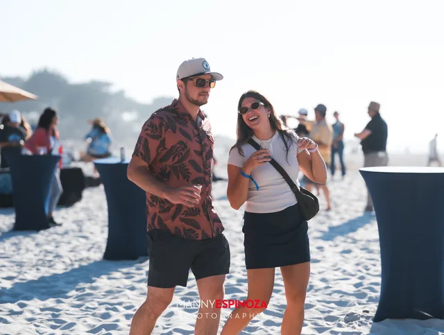 A guest holding a glass and laughing near the tables at Walk for Freedom 2026 on Carmel Beach