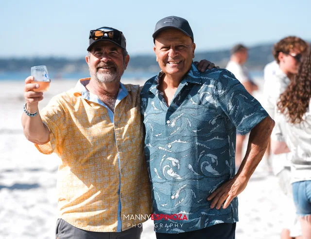 Two men in Hawaiian shirts raising their glasses at Walk for Freedom 2026 on Carmel Beach